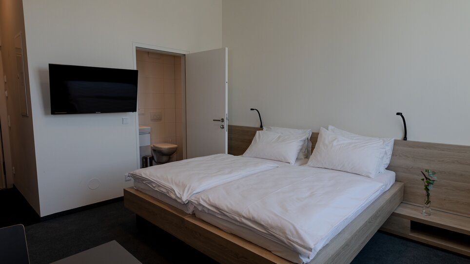 Vista di una camera per gli ospiti con letto matrimoniale e TV. | © Tomo-Tec Immo GmbH