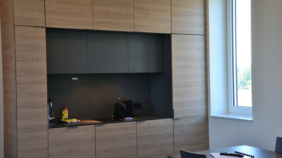 Cucina in un appartamento hotel con armadietti in legno e una finestra. | © Tomo-Tec Immo GmbH
