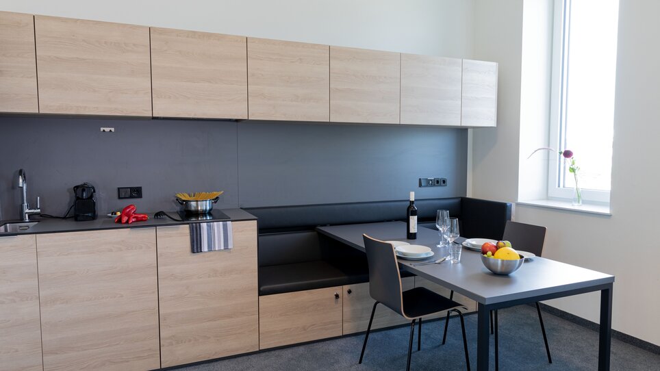 Cucina con tavolo, sedie e ciotola di frutta nel TT-Rooms Apartment-Hotel. | © Tomo-Tec Immo GmbH