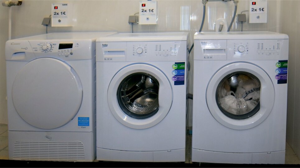 Two washing machines and a dryer in a laundry room. | © Alfred Chyba