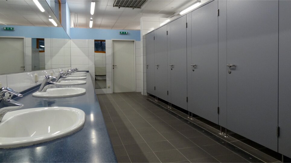 View of a public restroom with sinks and stalls. | © Alfred Chyba 