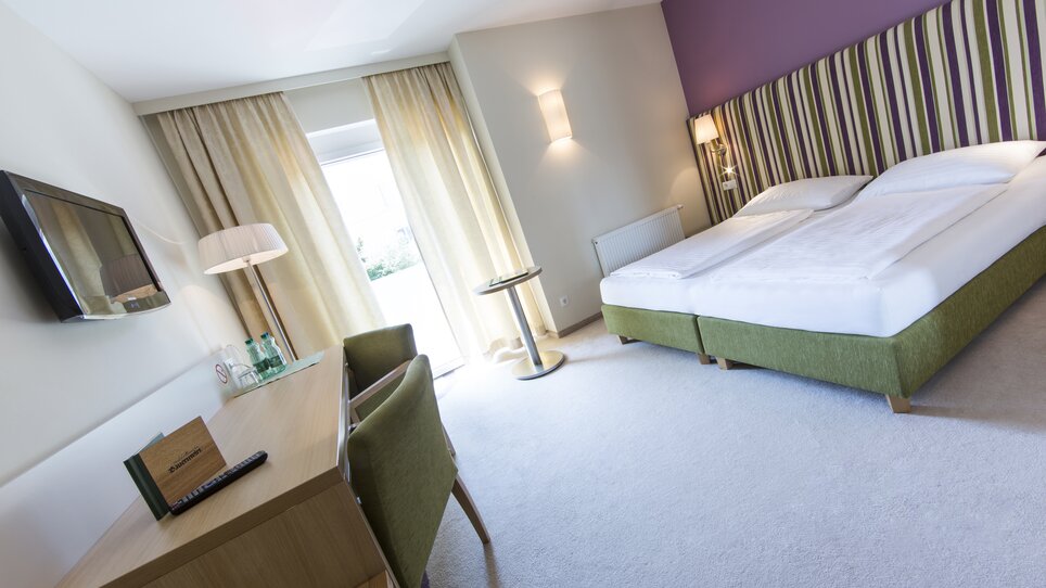 Helles, modernes Hotelzimmer mit Doppelbett und Schreibtisch. | © Bauernwirt 