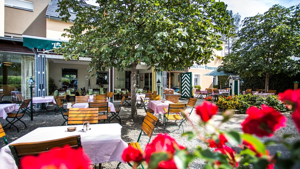 Terrasse des Bauernwirts Graz mit Tischen und Blumen. | © Rothwangl Photography