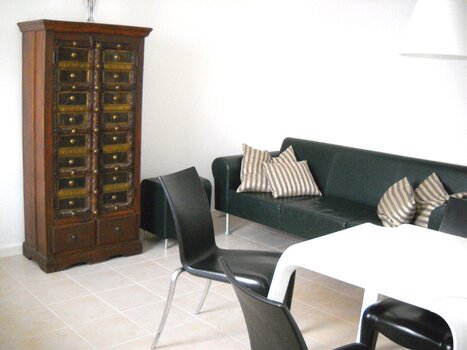 Interno moderno con divano nero, tavolo e armadietto antico. | © Domizil Familiaer