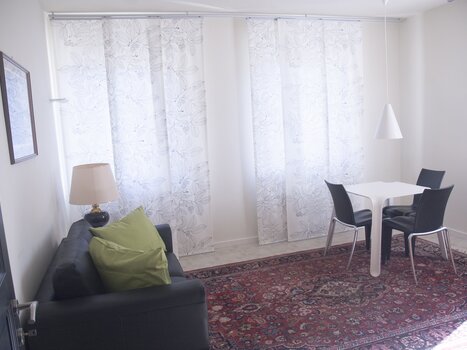 Stanza luminosa con divano, tavolo e sedie. | © Domizil Familiaer