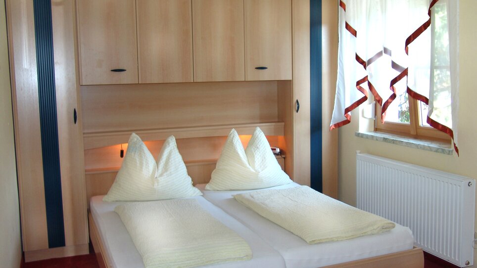 Ein Zimmer mit Doppelbett und Holzschränken in der Pension Scherwirt. | © Scherwirt