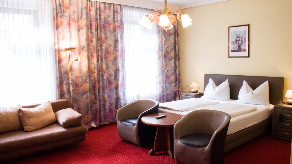 Camera d'hotel elegante con letto matrimoniale, divano e zona salotto. | © Hotel Alter Telegraf