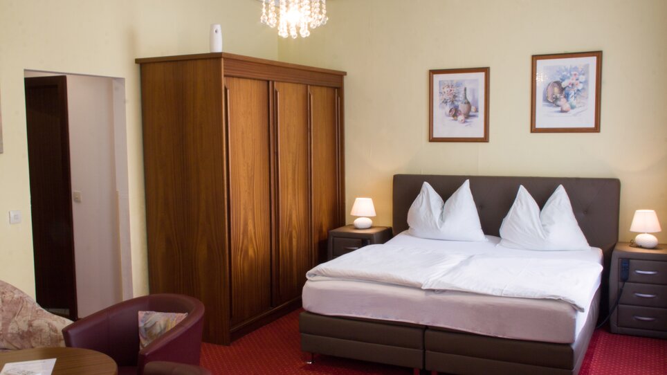 Una camera con letto matrimoniale, armadio e sedie. | © Hotel Alter Telegraf