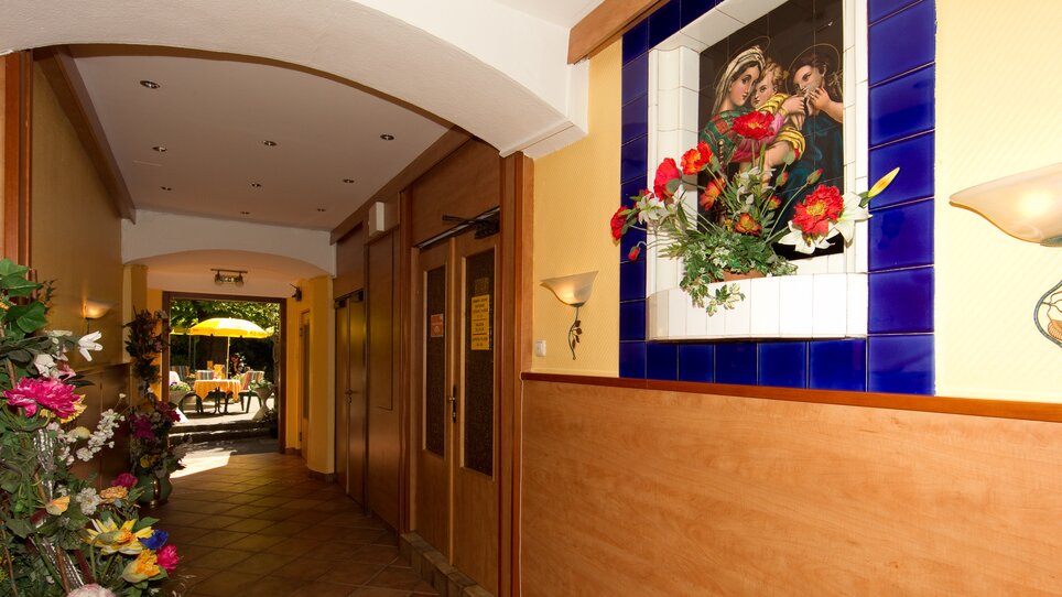 Un corridoio nell'Hotel Alter Telegraf con opere d'arte e fiori. | © Foto Schmickl