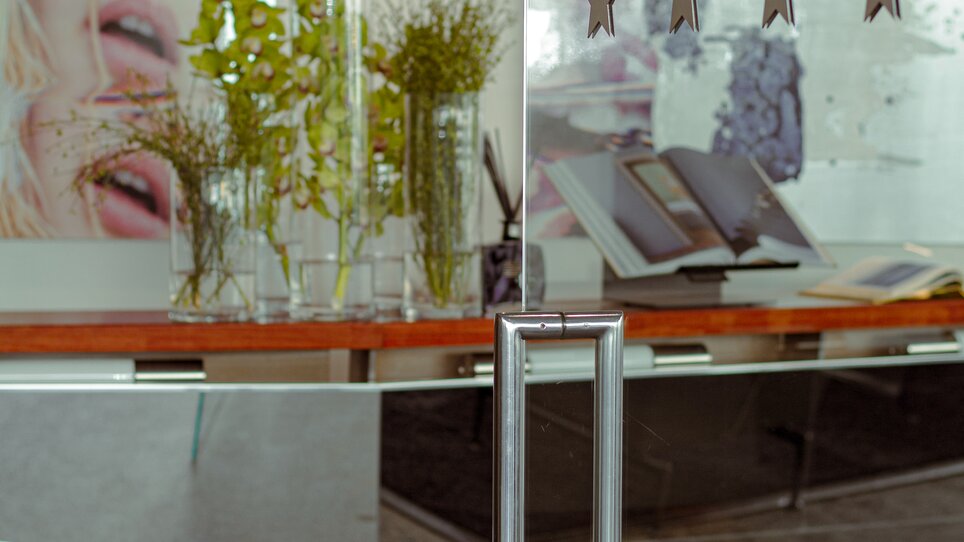 Durchsichtige Glastür mit Pflanzen und Kunst in einem modernen Foyer. | © Augarten Art Hotel