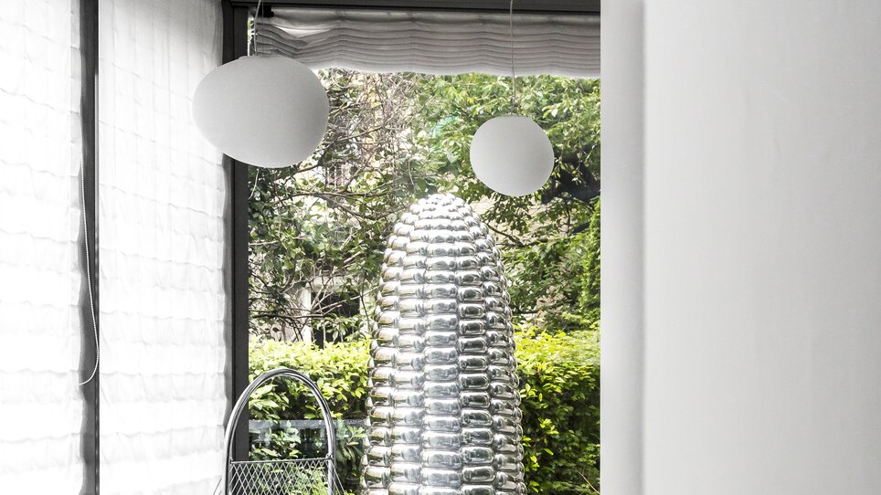 Ein eleganter Essbereich mit Tischen, stilvollen Lampen und einer besonderen Skulptur im Augarten Art Hotel. | © Augarten Art Hotel