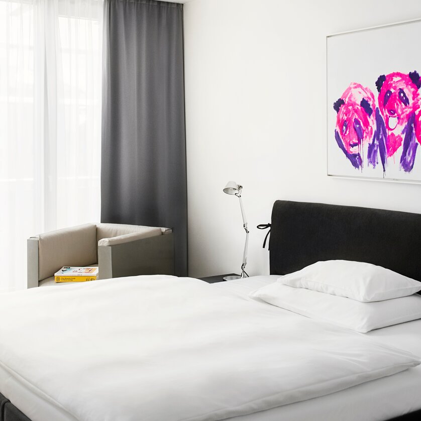 Business Suite | © Augarten Art Hotel Helles Schlafzimmer mit Kunstwerk, Bett und Sessel. | © Augarten Art Hotel