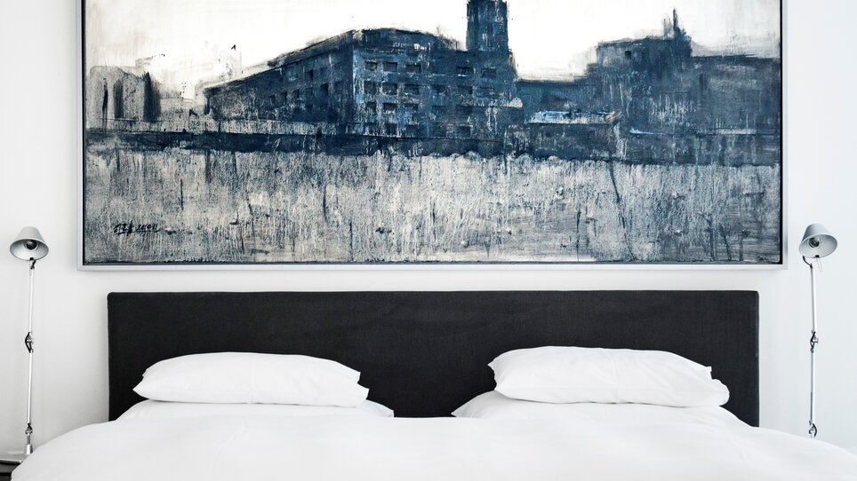 Ein stilvolles Schlafzimmer mit einem großen Gemälde über dem Bett. | © Augarten Art Hotel