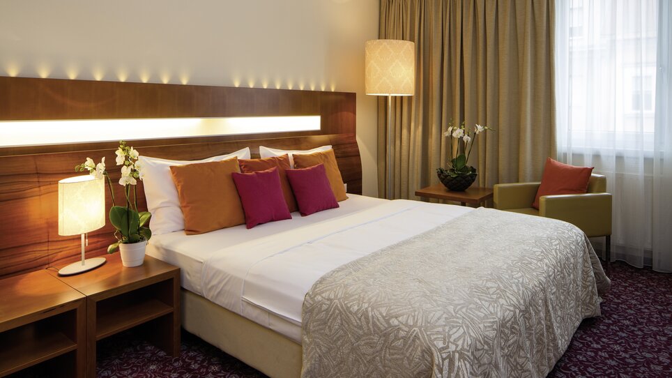 Ein stilvolles Hotelzimmer mit einem großen Bett und dekorativen Kissen. | © Austria Trend Hotel Europa Graz