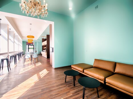 Bright lounge area with turquoise walls and brown sofa. | © B&B Hotels 2023