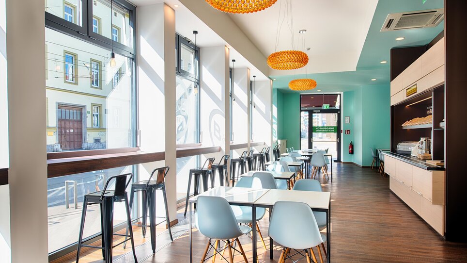 Innenbereich eines Bistros mit Stühlen, Tischen und Fenstern. | © B&B Hotels 2023