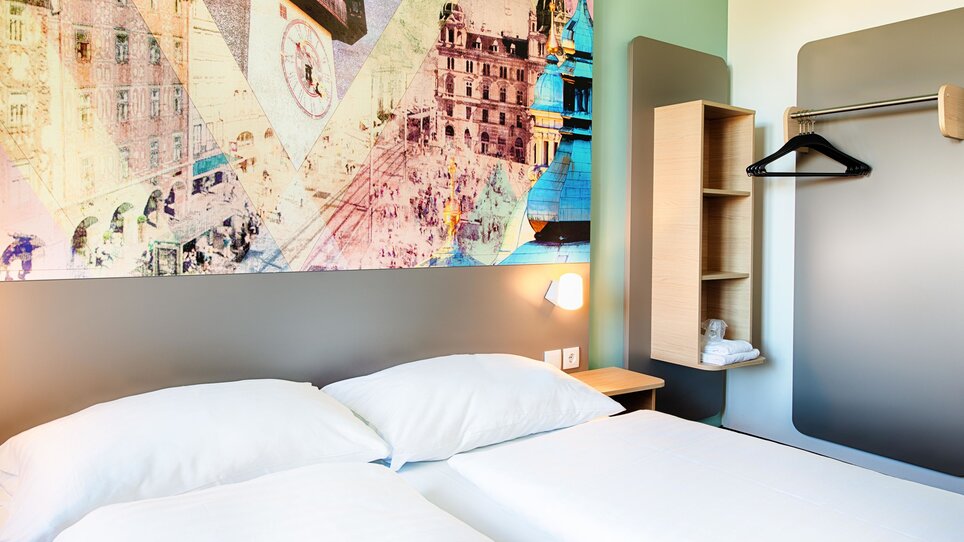 Zimmer im B&B Hotel Graz-Hbf mit Doppelbett und Wandbild. | © B&B Hotels 2023