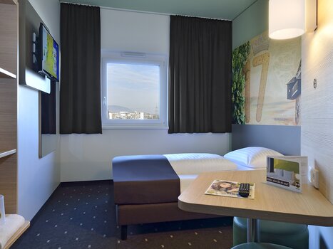 Vista di una camera singola con TV e tavolo. | © B&B Graz City Süd