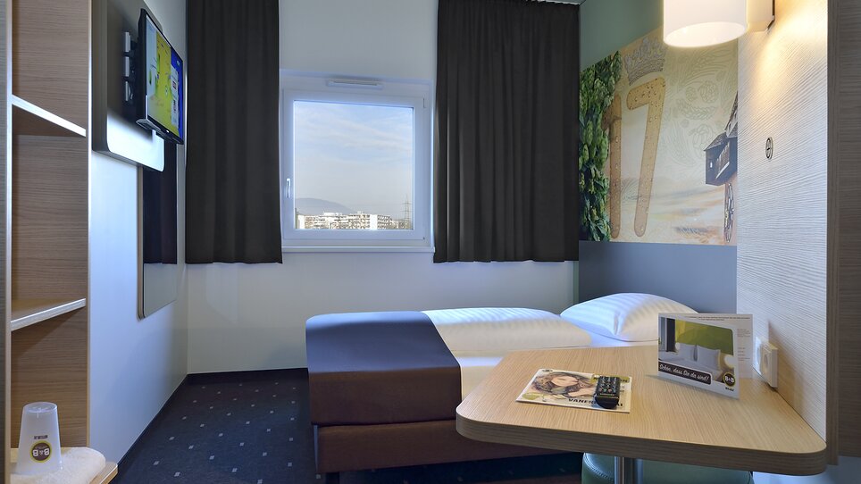 Vista di una camera singola con TV e tavolo. | © B&B Graz City Süd