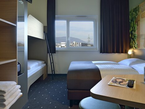 Vista di una camera con letto matrimoniale e un letto a castello. | © B&B Graz City Süd