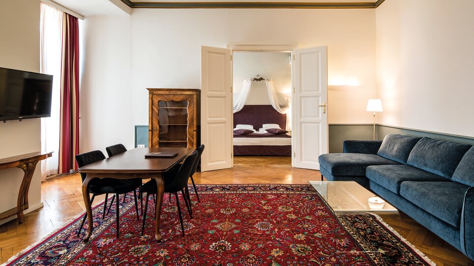 Ein geräumiger Wohnbereich mit Tisch, Stühlen und Blick auf das Schlafzimmer. | © Robert Illemann