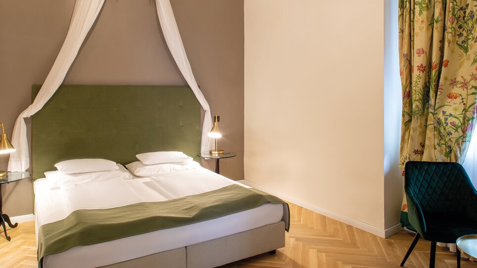 Ein stilvolles Schlafzimmer mit zwei Betten, Nachtischlampen und einem bequemen Stuhl. | © Robert Illemann