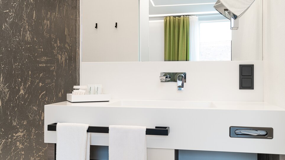 Bagno luminoso con lavandino, specchio e asciugamani. | © Chrizz Rooms