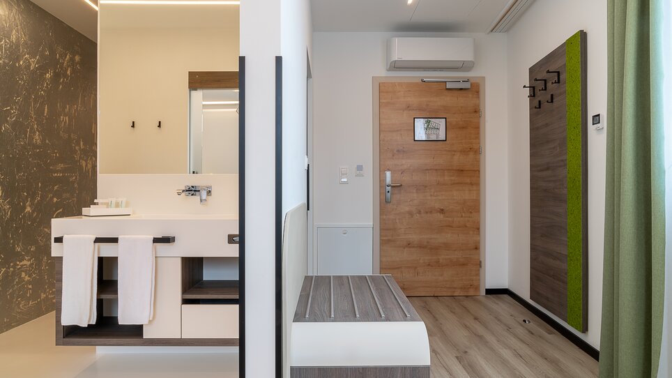 Vista su un ampio ingresso e un bagno moderno con lavabo e doccia. | © Chrizz Rooms