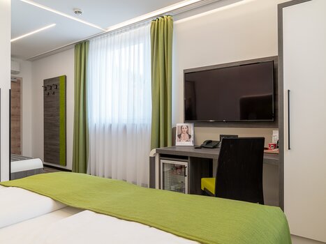 A modern hotel room featuring a TV, desk, and window. | © Chrizz Rooms