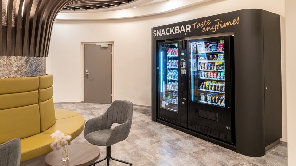 Un'area snack con distributore automatico e posti a sedere. | © Chrizz Rooms