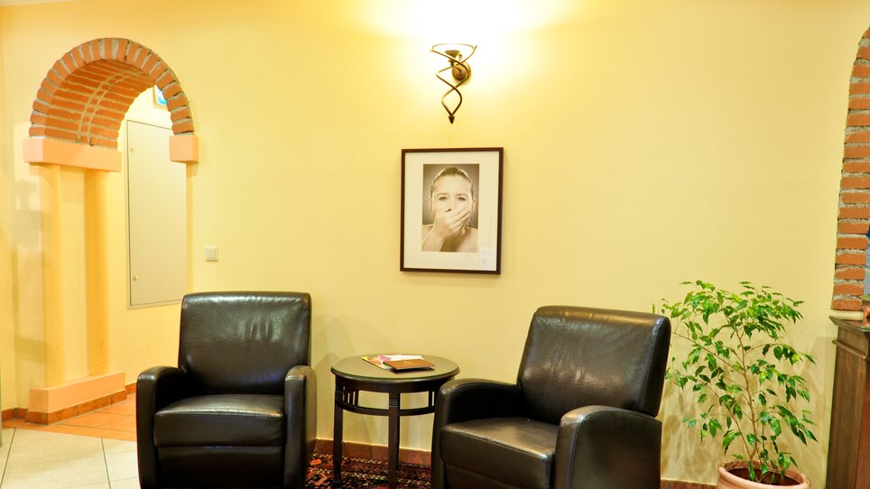 Two black chairs and a table in a room with plants and a wall picture. | © Hotel Feichtinger