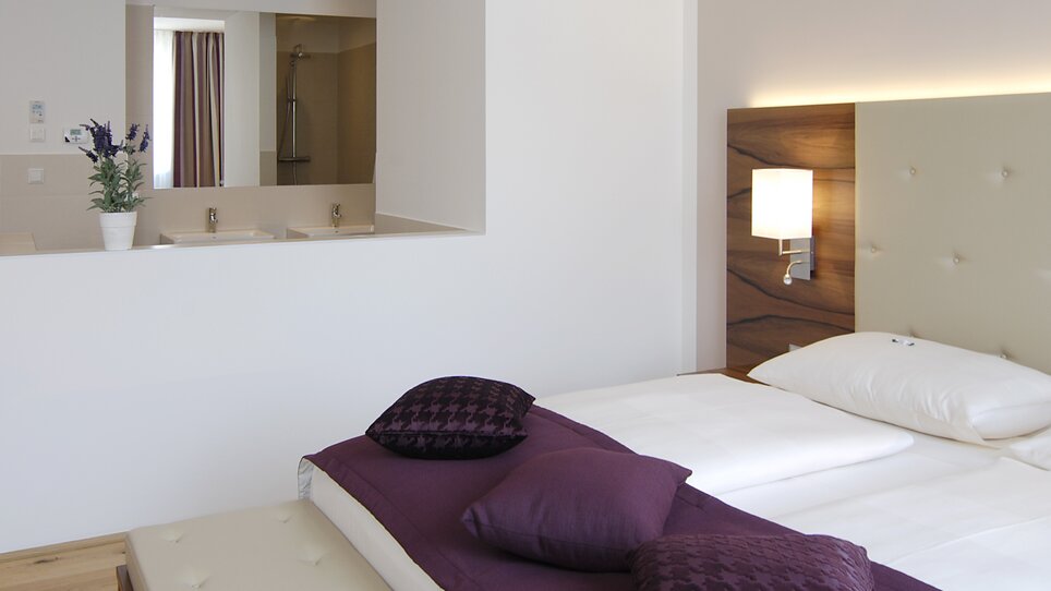 Bedroom with bed and bathroom in the background. | © Hotel Feichtinger
