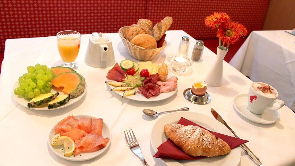 A rich breakfast featuring fruits, bread, cold cuts, and drinks on a table. | © Hotel Feichtinger