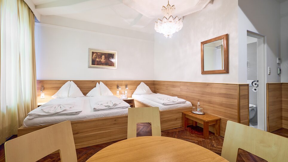 Ein Hotelzimmer mit zwei Betten, Tisch und Bad. | © EKONO by Leva Hotel Strasser