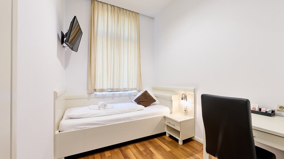 Einzelzimmer mit einem Bett, Schreibtisch und TV. | © EKONO by Leva Hotel Strasser
