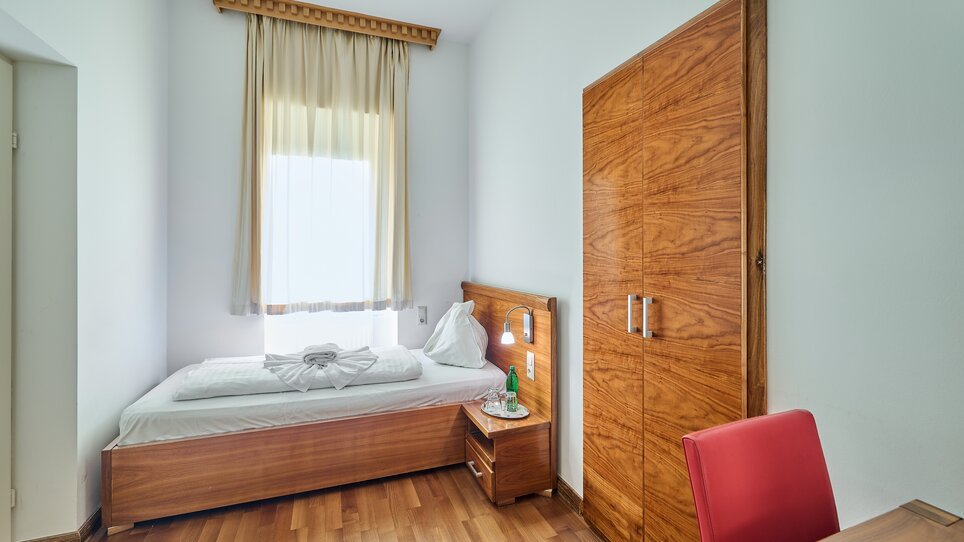 Einfaches Einzelzimmer mit Bett, Schreibtisch, Fenster und Schrank. | © EKONO by Leva Hotel Strasser