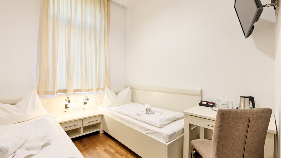 Zimmer mit zwei Betten, Tisch und Fernseher. | © EKONO by Leva Hotel Strasser