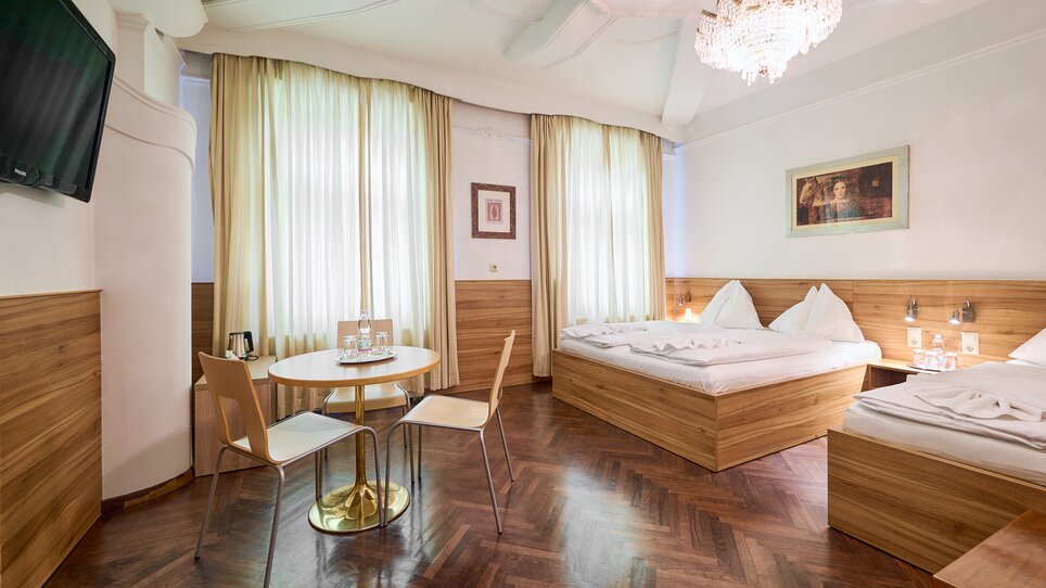 Ein Hotelzimmer mit Holzmöbeln, zwei Betten und einem Tisch. | © EKONO by Leva Hotel Strasser