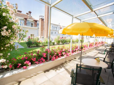 Terrazza con ombrelloni gialli e aiuole di rose. | © Gollner