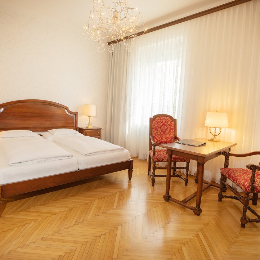 A bedroom with double bed, wooden furniture, and table with chairs. | © Gollner
