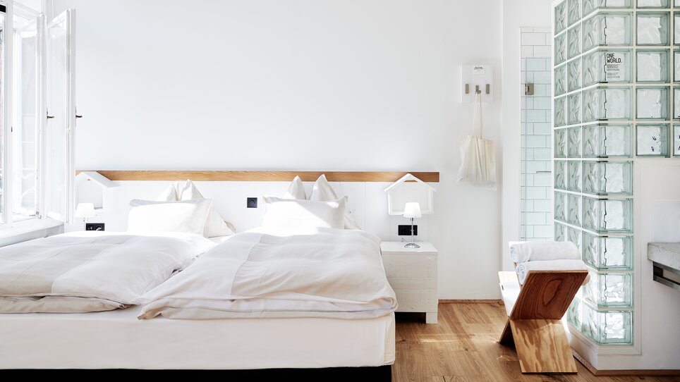 Schlafzimmer mit Doppelbett, Glasdusche und Holzdetails.