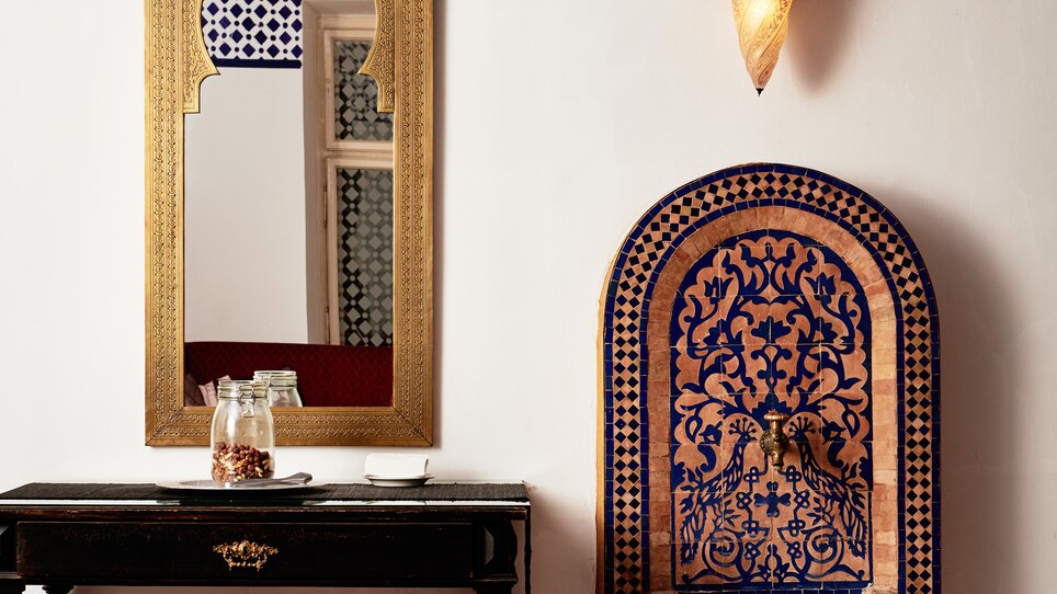 Ein traditionelles marokkanisches Zimmer mit einem Brunnen und Spiegel.