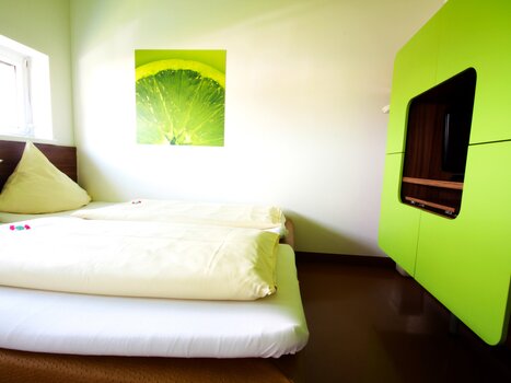 Ein helles Schlafzimmer mit zwei Betten und einem grünen Schrank.