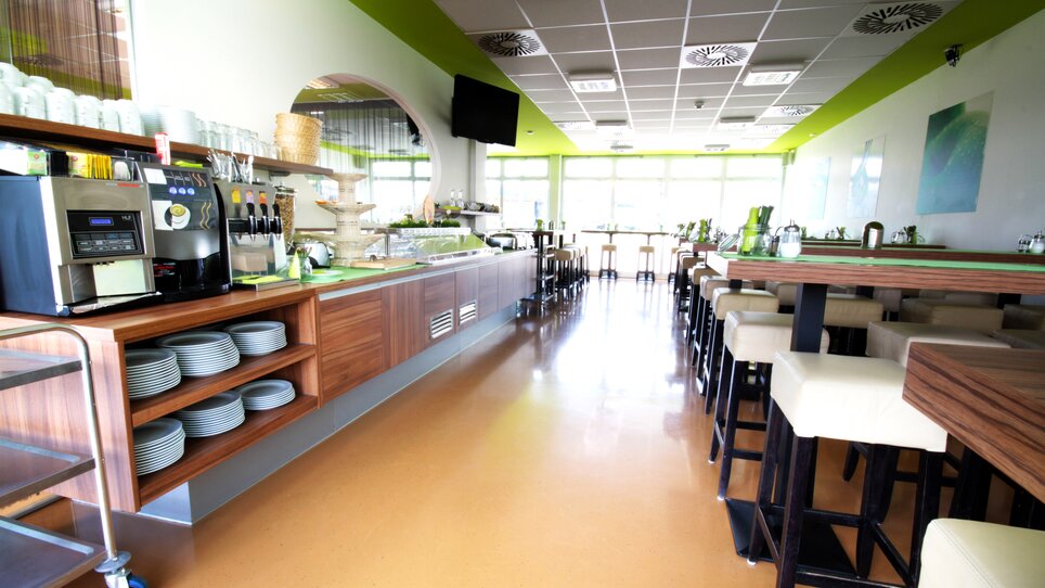 Einblick in das Restaurant mit Tischen, Bar und Kaffeemaschine. | © Hotel Greenrooms