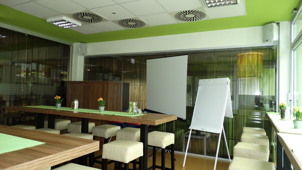 Ein Tagungsraum mit Tischen, Stühlen, Flipchart und Projektor.