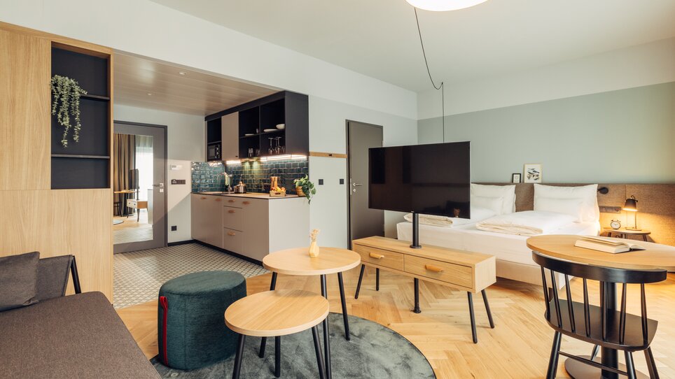 Modernes Zimmer mit Küche, TV und Schlafbereich im harry's home Graz-Smart City. | © harry's home Graz-Smart City - Daniel Zangerl