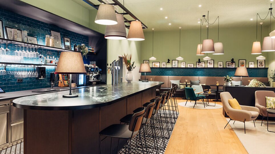 Eingangsbereich eines Cafés mit einer Bar und Sitzgelegenheiten im harry's home Graz-Smart City. | © harry's home Graz-Smart City- Daniel Zangerl