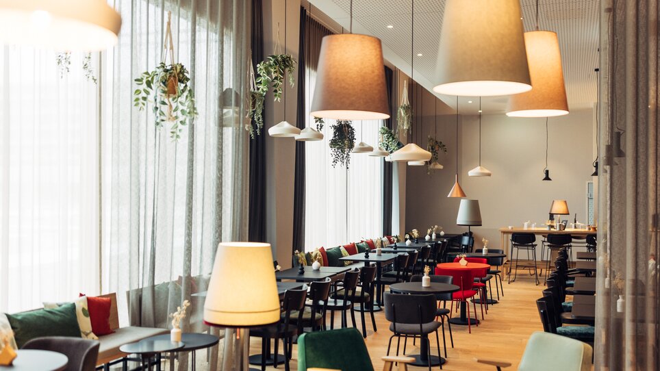 Interior of a café with tables, chairs, and lighting. | © harry’s home hotels - Daniel Zangerl