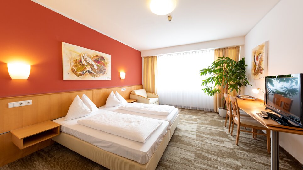 Modernes Zimmer mit zwei Betten, Fernseher und Pflanzen. | © Harry Schiffer