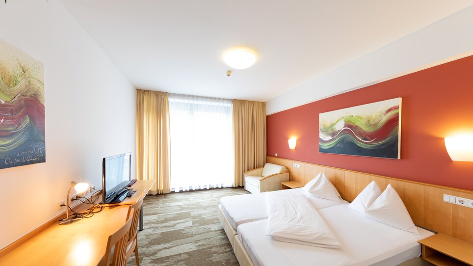 Ein helles Doppelzimmer mit großen Fenstern und modernen Möbeln. | © Harry Schiffer